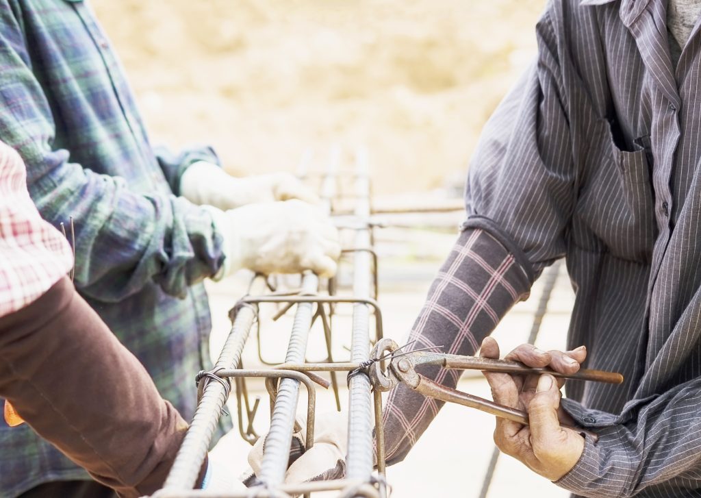 construction workers are installing steel rods in reinforced con